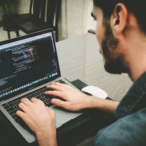 Picture of a man coding on a laptop